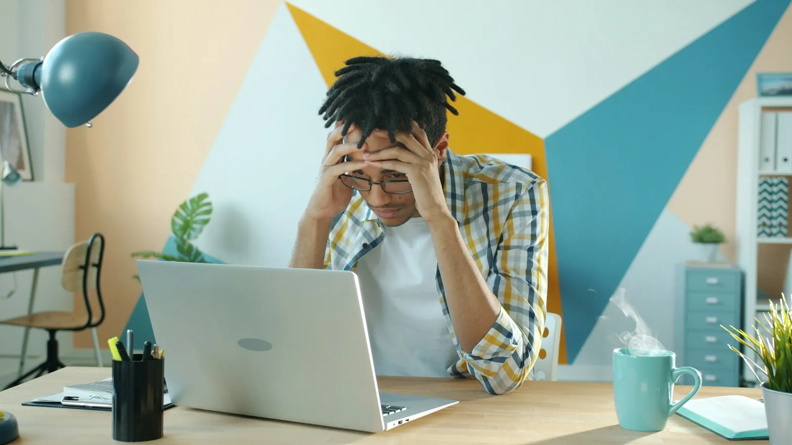 Frustrated business owner holding his head at a desk in front of a laptop