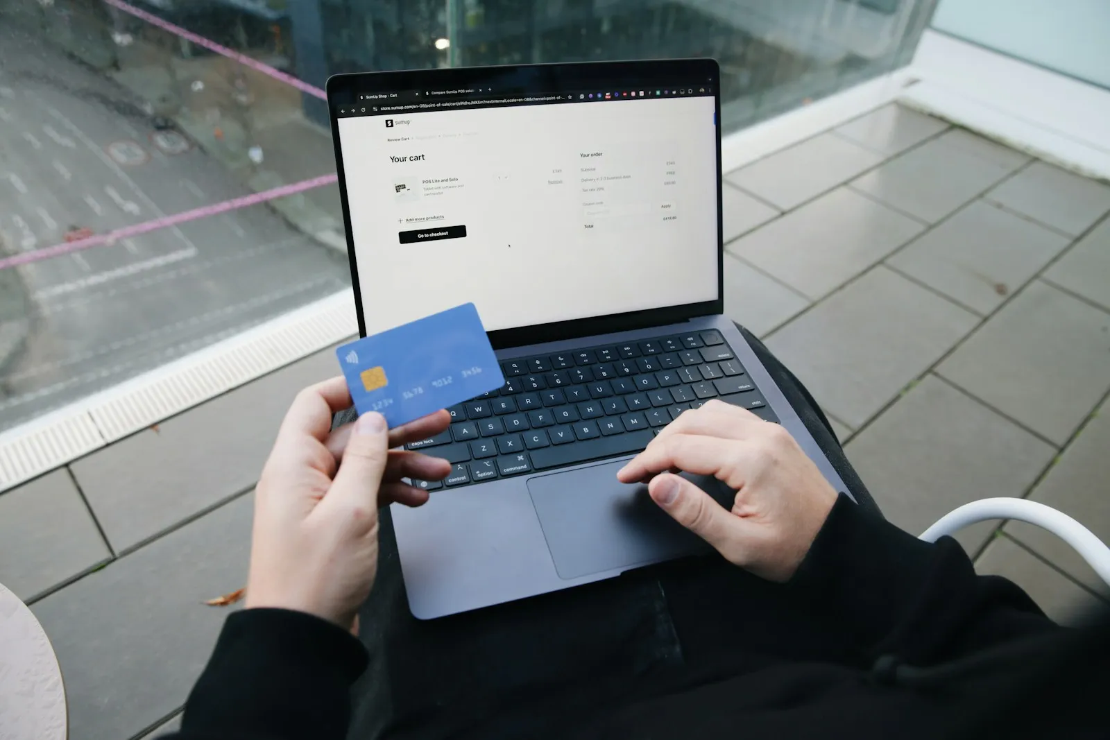 Customer holding a credit card while completing an online checkout on a laptop