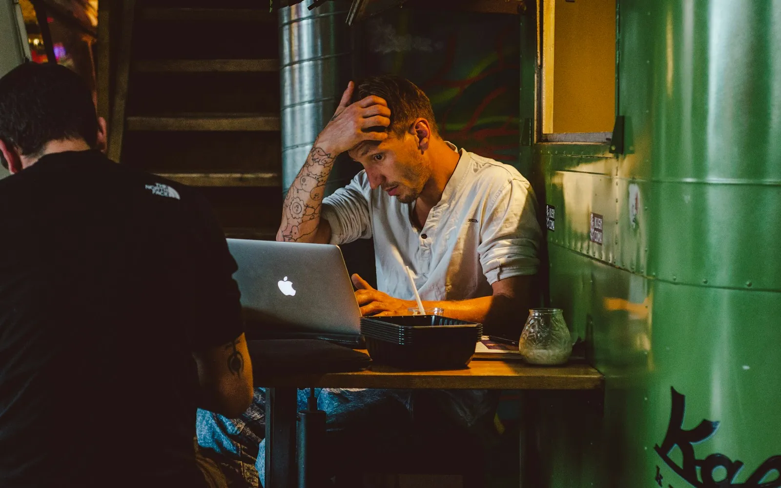 Man scratching his head while waiting on a slow website on his laptop