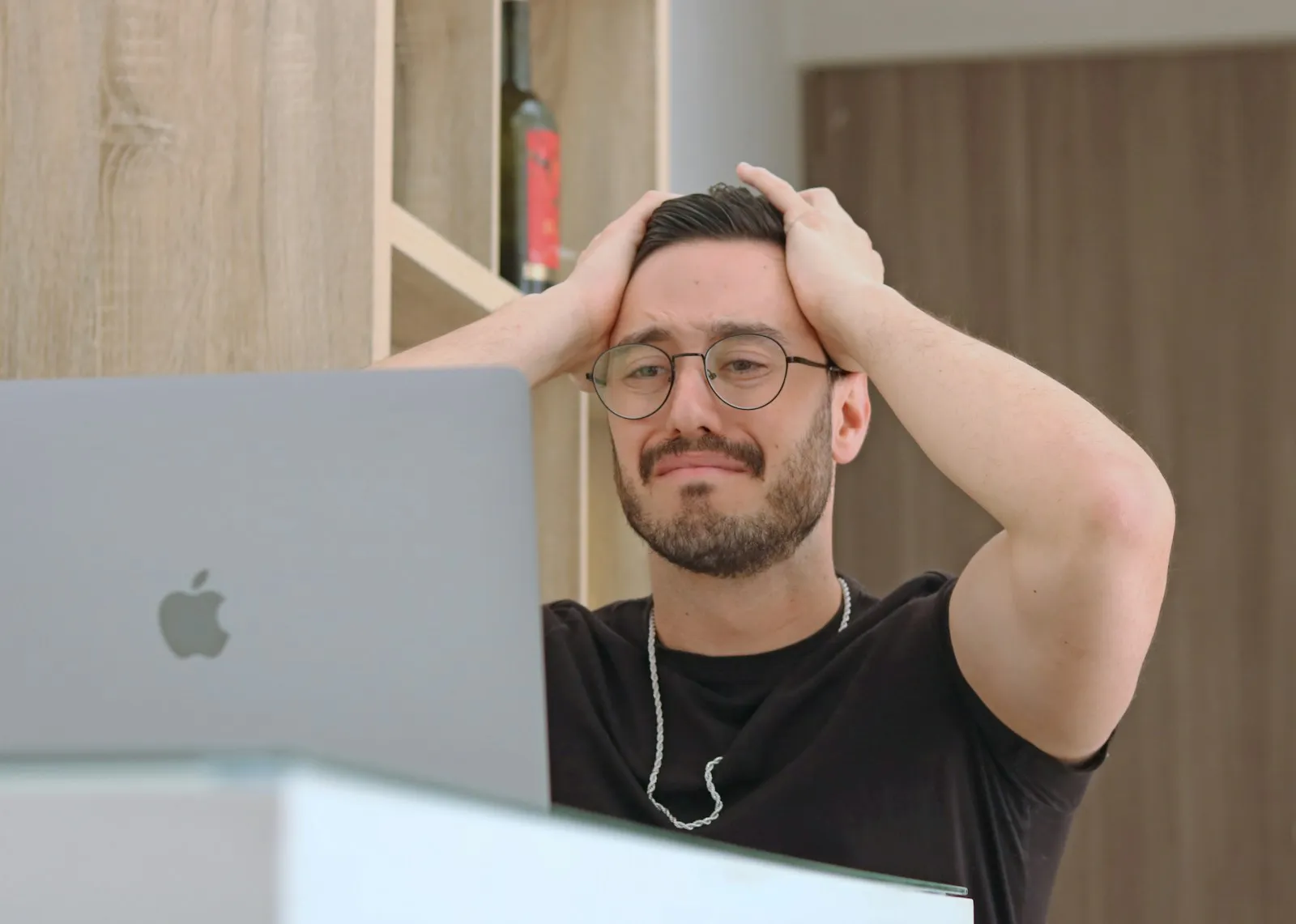 Confused man holding his head while looking at a laptop screen