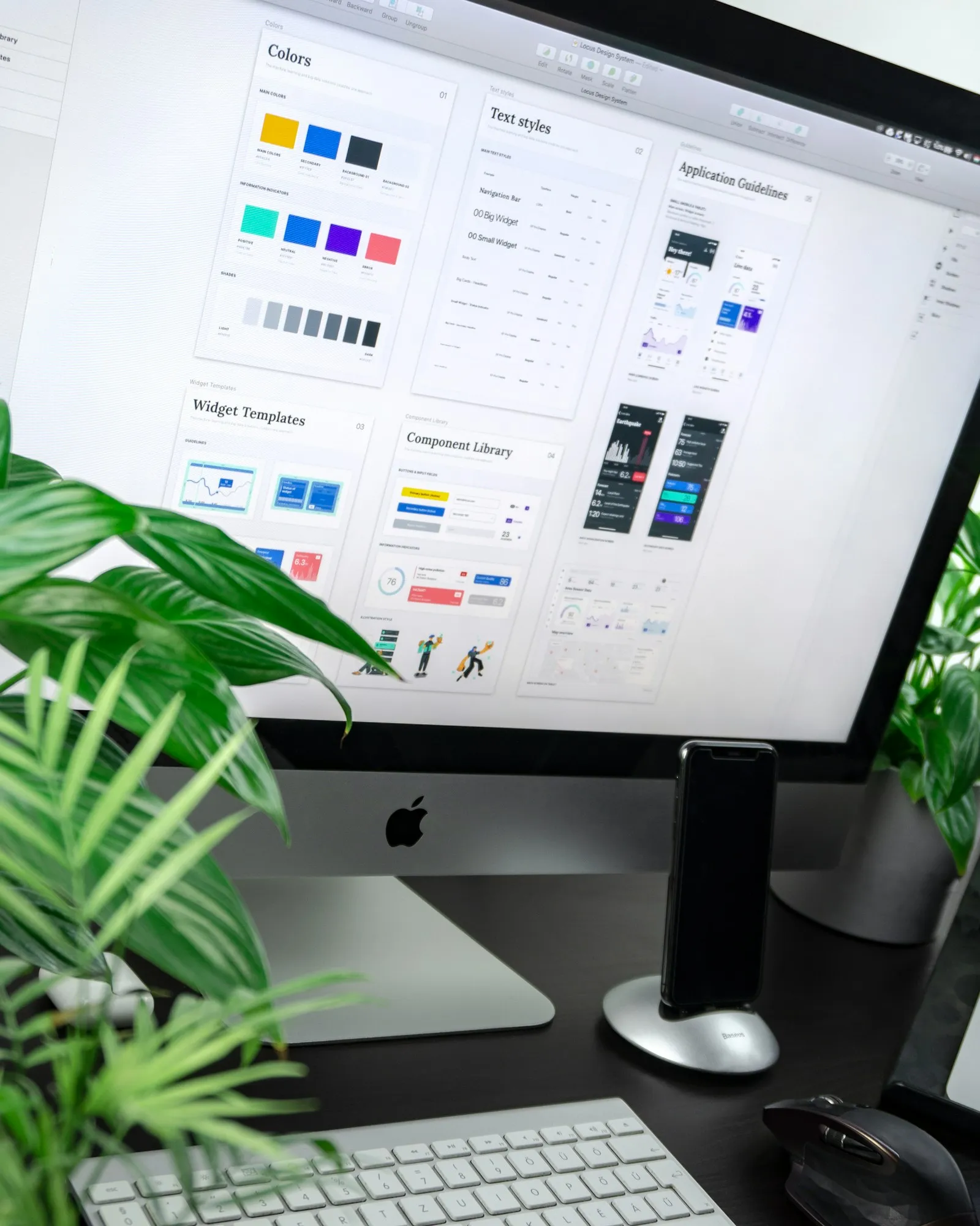 Desktop monitor displaying a website design system with colour swatches and components